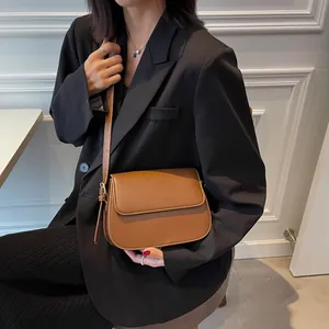 Brown faux leather crossbody saddle bag shown with a black blazer for a minimalist look