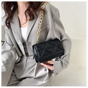 Detail of black quilted crossbody bag with textured triangle pattern and gold chain strap