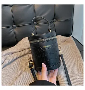 Details der schwarzen Zylindertasche mit Krokodil-Prägung und goldenen Metallelementen