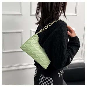Close-up of mint green quilted bag with chunky gold chain strap on model's shoulder
