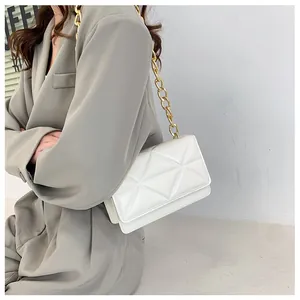 Detail of white quilted geometric shoulder bag with a chunky gold metal chain strap