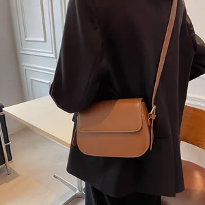 Close-up of caramel brown leather saddle bag with adjustable strap and gold metal hardware
