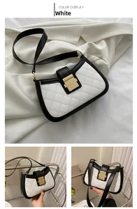 Détail du sac bandoulière blanc matelassé avec bordure noire et boucle dorée en métal
