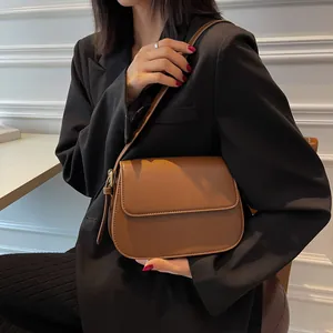 Close-up of caramel matte leather saddle bag worn over the shoulder with retro minimalist design