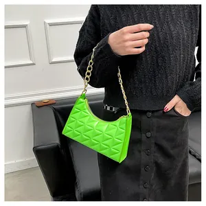 Detail of neon green quilted baguette bag featuring a bold gold chain handle detail