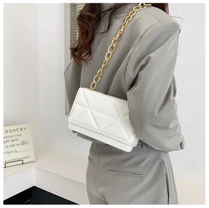 Detailed view of white quilted crossbody bag with stylish gold chain strap on shoulder