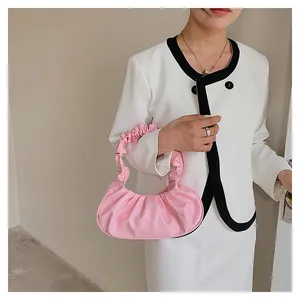 Close-up of pink pleated cloud shoulder bag worn with a white blazer for fashion look