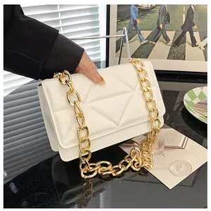 Detail of white quilted crossbody bag with chunky gold chain strap and flap closure