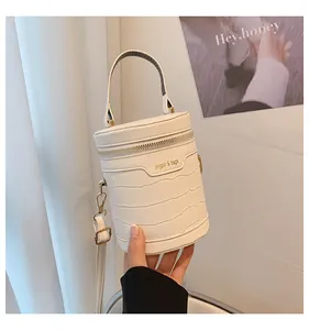 Detailansicht der weißen Zylindertasche mit Krokodilprägung und praktischem Tragegriff