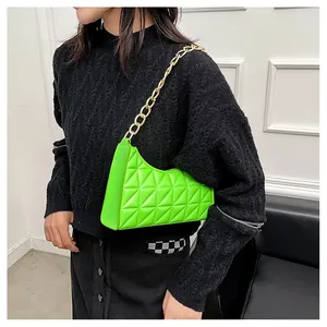 Detailed view of neon green quilted leather underarm bag with chunky gold chain strap