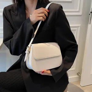 Minimalist white leather saddle bag shown against a black suit for elegant contrast