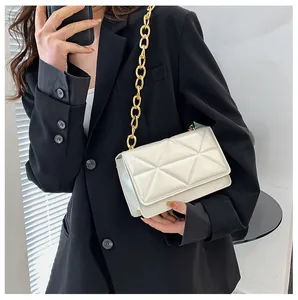 Detail of white geometric embossed crossbody bag with chunky gold chain on black blazer