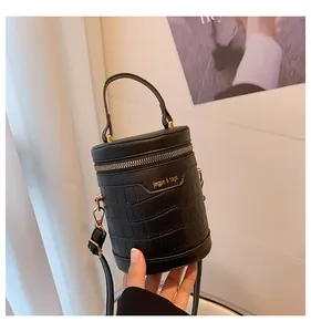Detail einer schwarzen Zylindertasche mit Krokoprägung, Goldbeschlägen und Logo