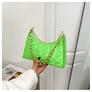 Detail of neon green quilted handbag with chunky gold chain handle and zipper closure