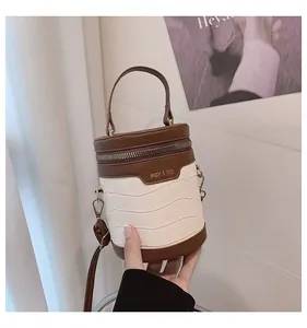 Detailaufnahme der Kontrast-Zylindertasche mit weißer Krokoprägung und braunem Leder
