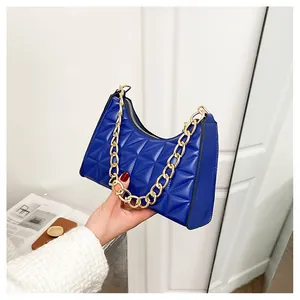 Detail of navy blue quilted crescent bag with textured gold chain handle and glossy finish
