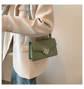 Close-up of mint green crocodile-pattern square bag with gold buckle detail