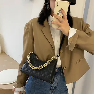 Sac à bandoulière matelassé noir pour femme avec grosse chaîne dorée porté avec un blazer