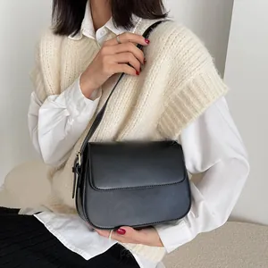Close-up of matte black leather saddle bag with adjustable strap on a model