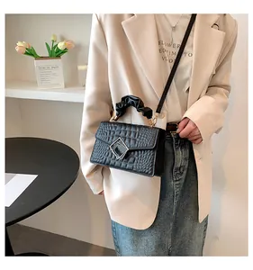Detail of black crocodile texture handbag featuring a silver geometric metal buckle
