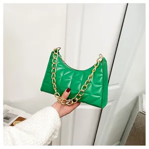 Detail of bright green quilted underarm bag featuring a chunky gold metal chain strap