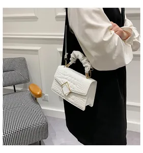 Detail showing white crocodile pattern handbag with unique scrunchie handle on model
