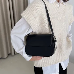 Classic black saddle bag worn by a model with smooth matte finish and gold metal hardware
