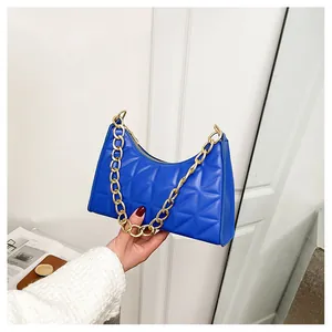 Detail of bright blue quilted underarm bag with a bold gold chain handle and zipper