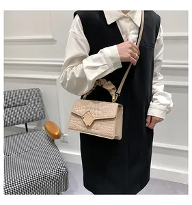 Detail of beige crocodile pattern handbag with gold hardware and ruched top handle