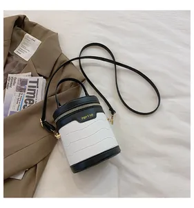 Details der schwarz-weißen Zylindertasche mit Krokoprägung und goldenen Beschlägen
