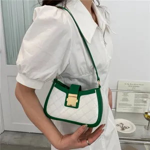 Sac à bandoulière bicolore avec bordure verte et fermoir doré porté par le mannequin