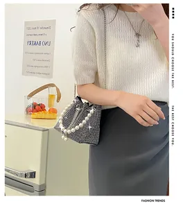 Detail of rhinestone bucket bag with pearl handle and metal chain on a model