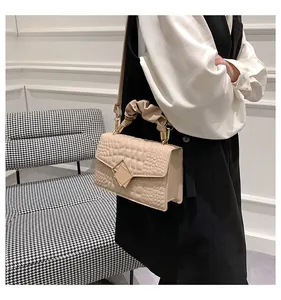 Detail of beige crocodile pattern handbag with pleated handle and golden diamond clasp