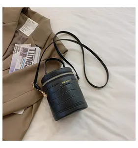 Detail einer schwarzen Zylindertasche mit Krokostruktur und Goldreißverschluss