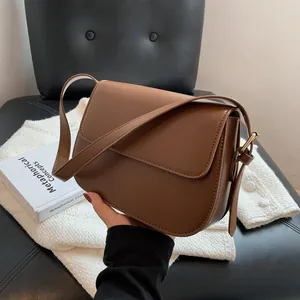 Detail of a vintage dark brown leather saddle bag with golden hardware and adjustable strap