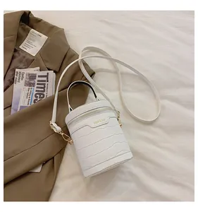 Draufsicht auf eine weiße Zylindertasche mit Krokoprägung, Gold-Reißverschluss und Schultergurt