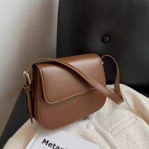 Detailed shot of a brown leather saddle bag with gold hardware on a leather chair