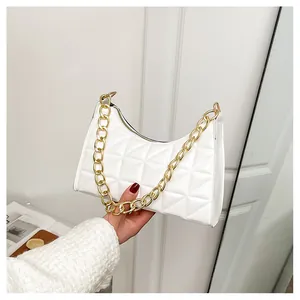 Detail of white quilted crossbody bag with thick gold chain strap and zipper closure