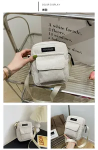 Detail view of off-white corduroy crossbody bag featuring a front pocket with logo label