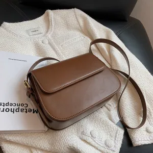 Detail of a brown leather saddle bag featuring fine stitching and metal buckles