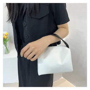 Minimalist white trapezoid handbag with contrasting black handles and sleek zip closure
