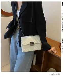 Close-up of white quilted crossbody bag with silver chain and vintage metal buckle