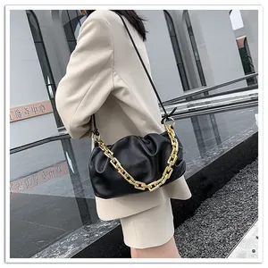 Detail of black pleated cloud bag featuring a chunky gold chain and leather shoulder strap
