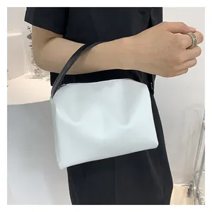Detail of minimalist white handbag with black handles worn by a fashion model