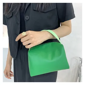 Detail of vibrant green PU leather handbag with zipper and minimalist handle held by model