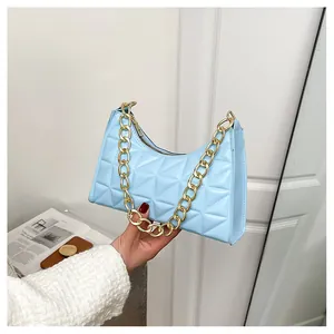 Detailed view of light blue textured leather underarm bag with chunky gold chain strap