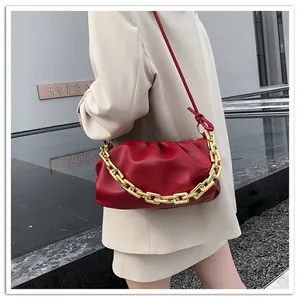 Detail view of burgundy pleated cloud bag with chunky gold chain strap on model
