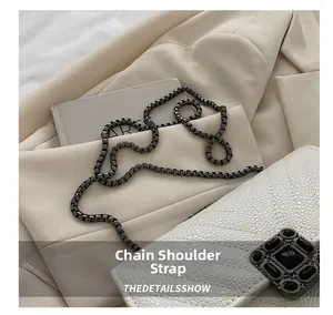 Detailed view of white lychee textured bag with decorative black gemstone buckle and chain