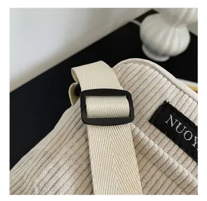 Close-up of beige corduroy shoulder bag showing woven strap and black plastic buckle