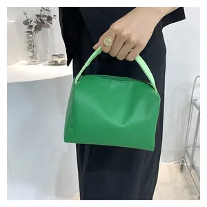 Detail shot of bright green minimalist handbag with top zipper and smooth synthetic leather